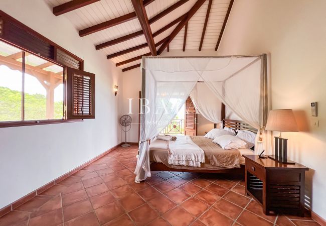 Grande chambre à coucher avec charpente apparente et mobilier en bois tropical