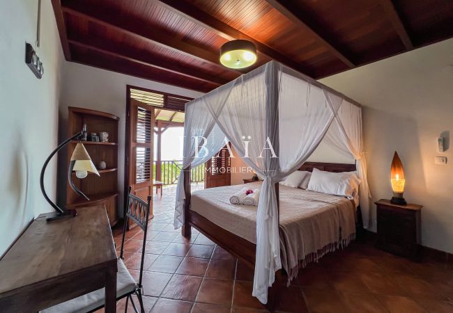 Grande chambre à coucher avec charpente apparente et mobilier en bois tropical
