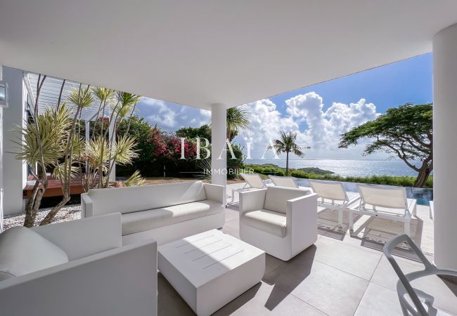 Salon extérieur blanc avec vue sur la piscine et la mer