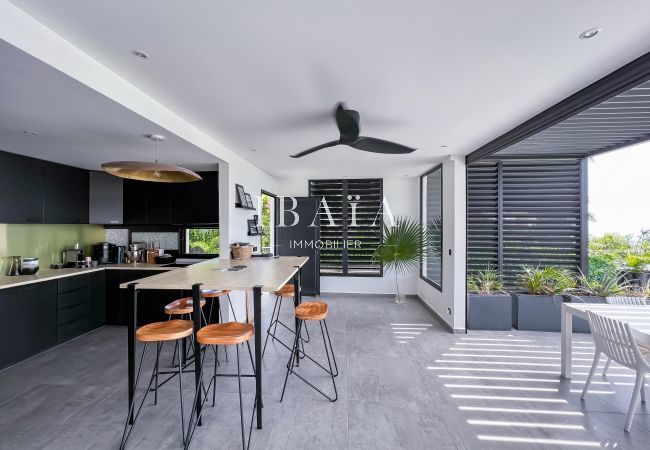 Cuisine américaine équipée avec ilot central ouverte sur une terrasse et la salle à manger