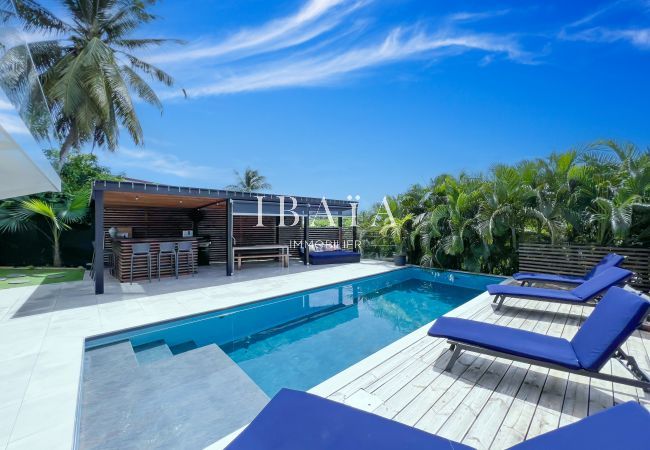 Pergola avec cuisine totalement équipée et coin repas autour de la piscine dotée de transats