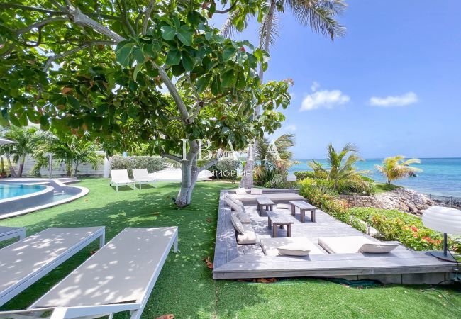 Salon et transat extérieur face à la mer dans un jardin tropical soigné