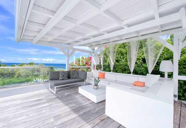 Vue du salon de jardin sous le patio sur une terrasse en bois avec vue sur la mer dans notre villa haut de gamme aux Antilles