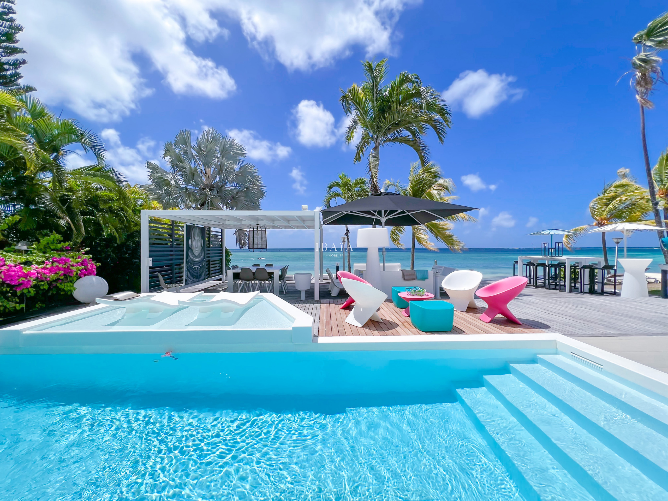 Piscine avec mobilier de jardin aux couleurs vives, pergola et table à manger offrant une vue sur mer, parasol et tables et chaises hautes - Villa hau