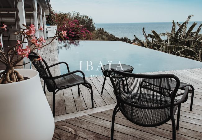 Chaises d'extérieur en bord de piscine offrant une vue imprenable sur la mer, dans une villa haut de gamme aux Antilles