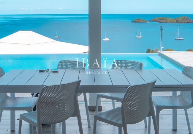 Table à manger extérieure offrant une vue imprenable sur la piscine, la mer et les îlets Pigeons, dans une villa de luxe aux Antilles