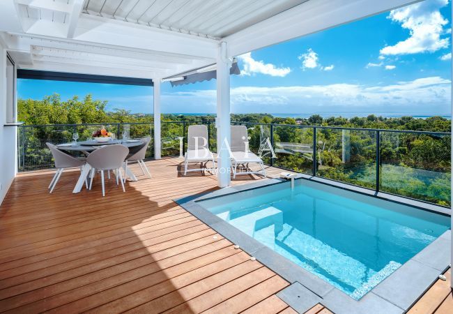 Terrasse avec une table à manger, des chaises et une petite piscine donnant sur un paysage naturel