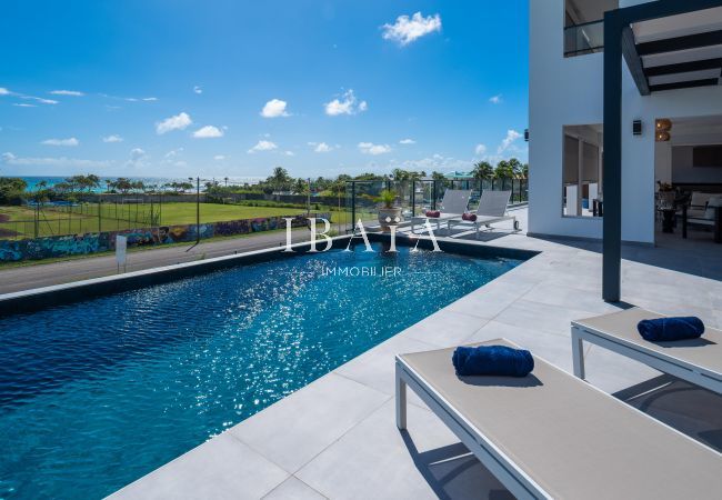 Piscine luxueuse d'une maison moderne avec vue sur l'océan et mur graffité.