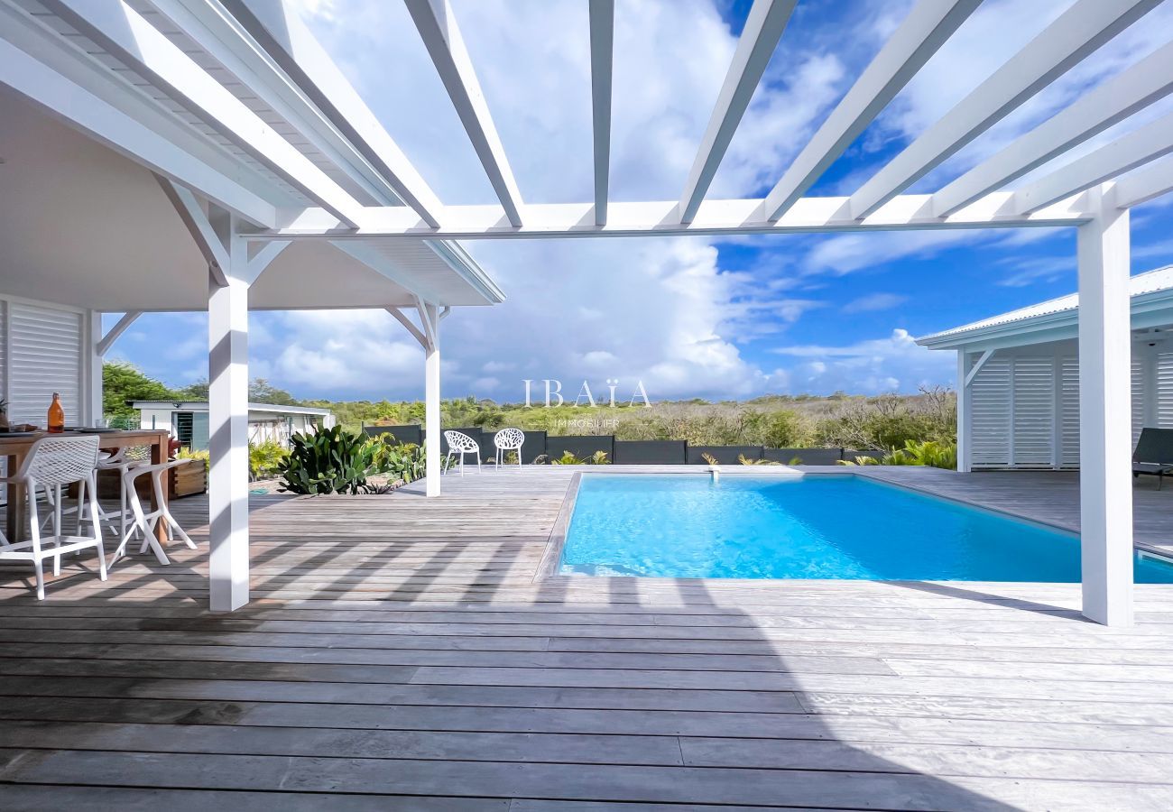 Vue de la terrasse avec piscine et pergolas dans une villa haut de gamme aux Antilles, pour une expérience de détente absolue