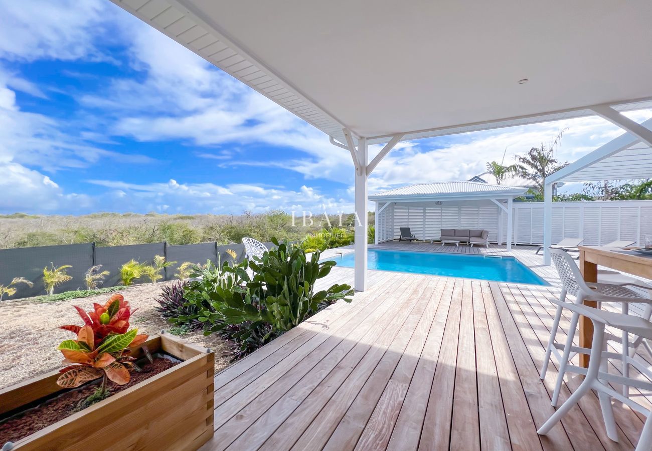 Vue sur le jardin et la piscine situés sous la terrasse dans une villa haut de gamme aux Antilles, pour une expérience de détente en plein air