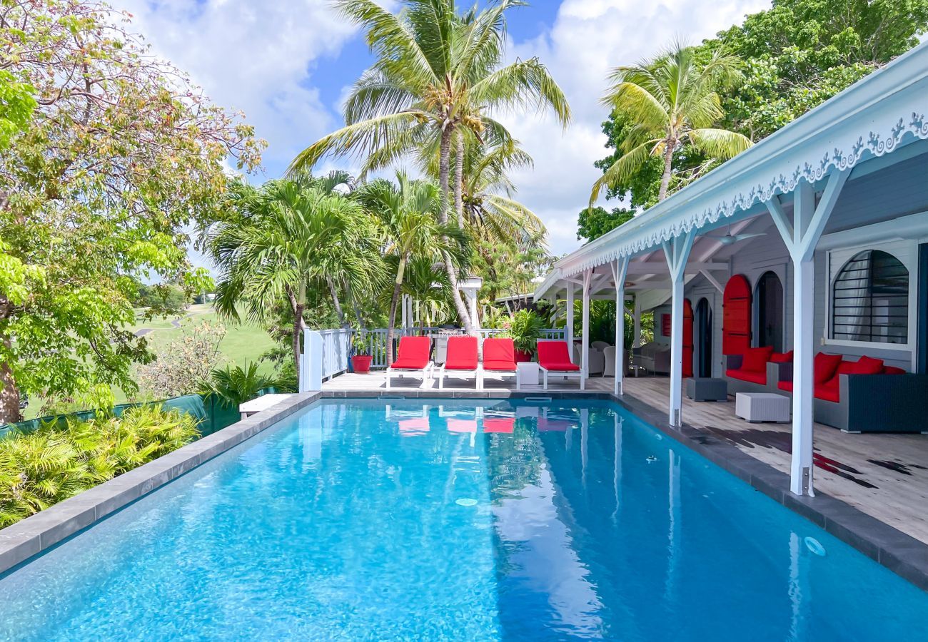 Transats rouges en bord de piscine sur terrasse en bois - Villa haut de gamme aux Antilles