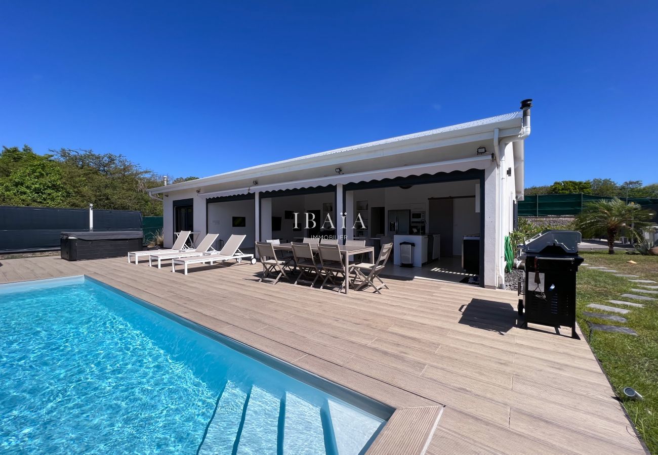 Terrasse de rêve avec piscine, transats, table à manger d'extérieur et barbecue dans une villa haut de gamme aux Antilles