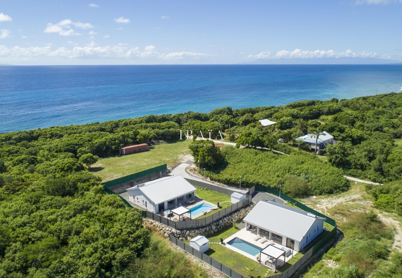 Vue aérienne des deux villas du hameau avec piscines et vue imprenable sur la mer, dans un cadre haut de gamme aux Antilles