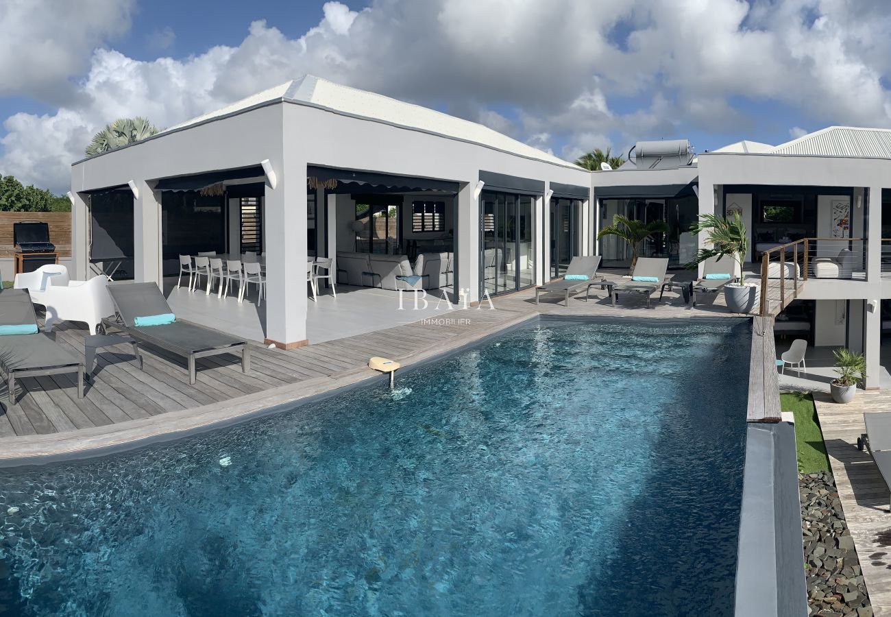 Vue aérienne villa luxe piscine débordement transats terrasse bois