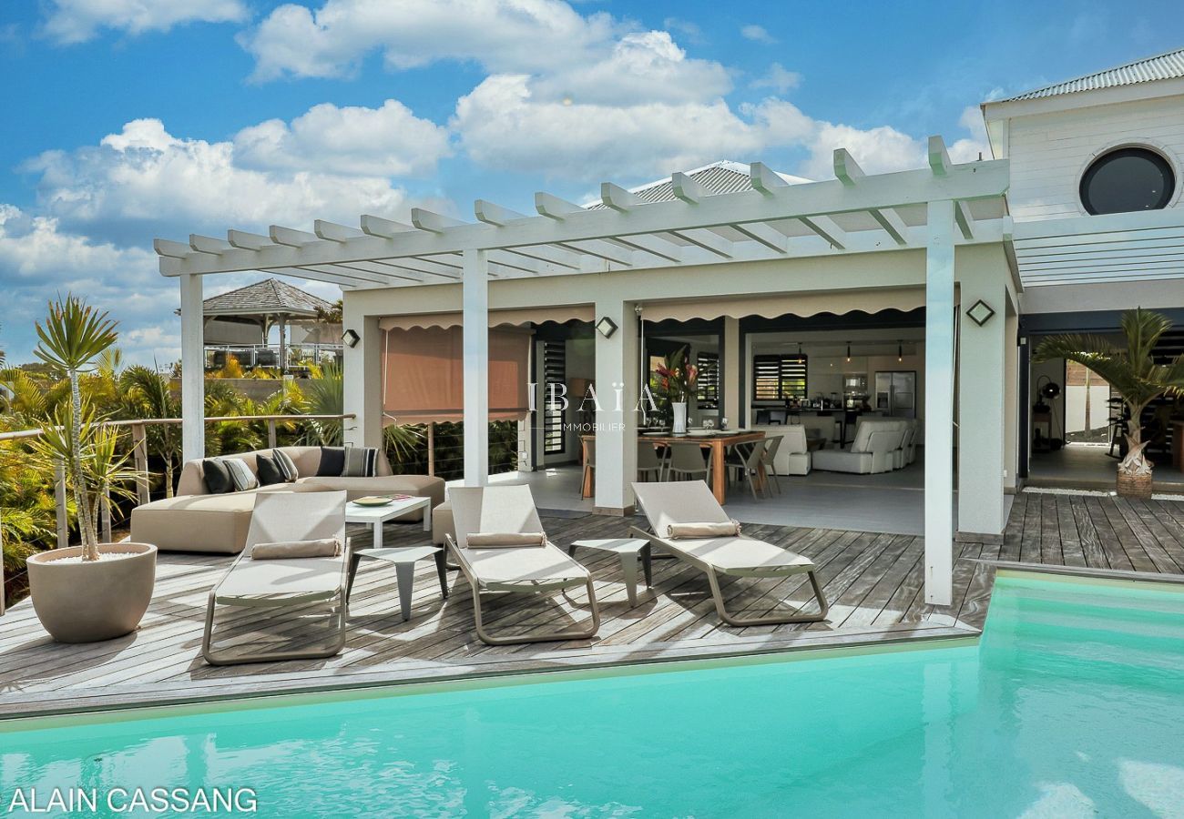 Vue sur une élégante terrasse avec piscine, espace salon et salle à manger en arrière-plan