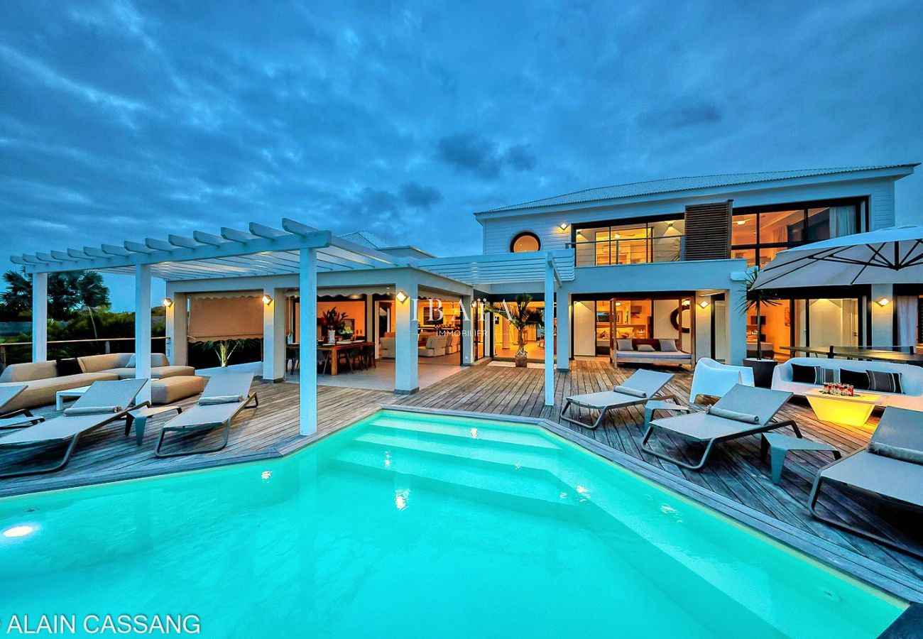 Vue nocturne d'une terrasse sophistiquée avec piscine éclairée et maison lumineuse