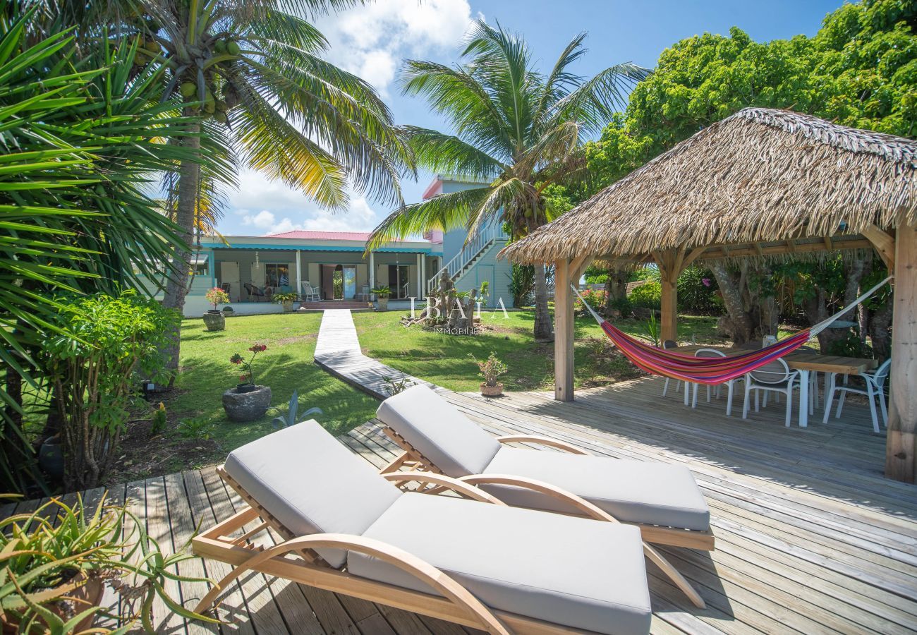 Transats, hamac et maison créole dans un jardin tropical