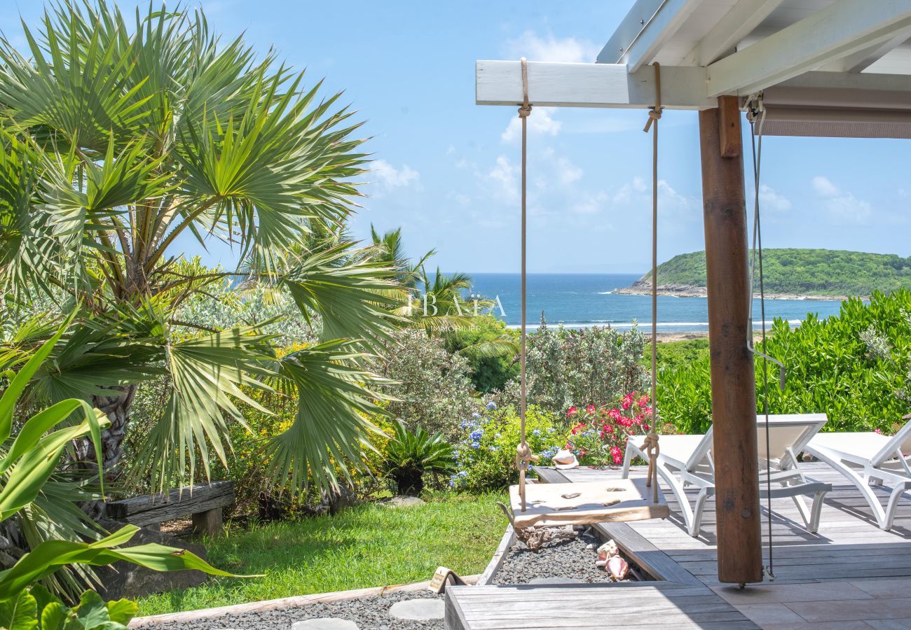 Balançoire en bois, transats, jardin tropical et vue mer